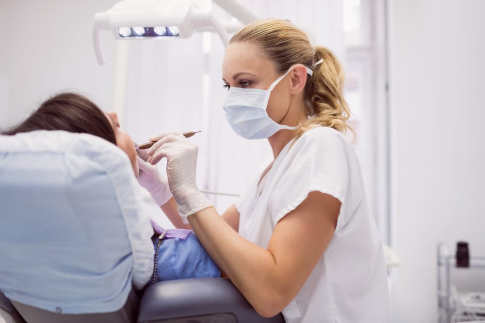 A dentist examining a patient in the treatment chair