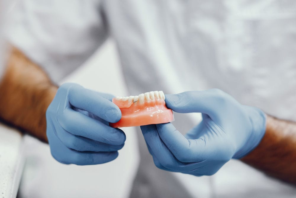 A dental technician holding a full denture